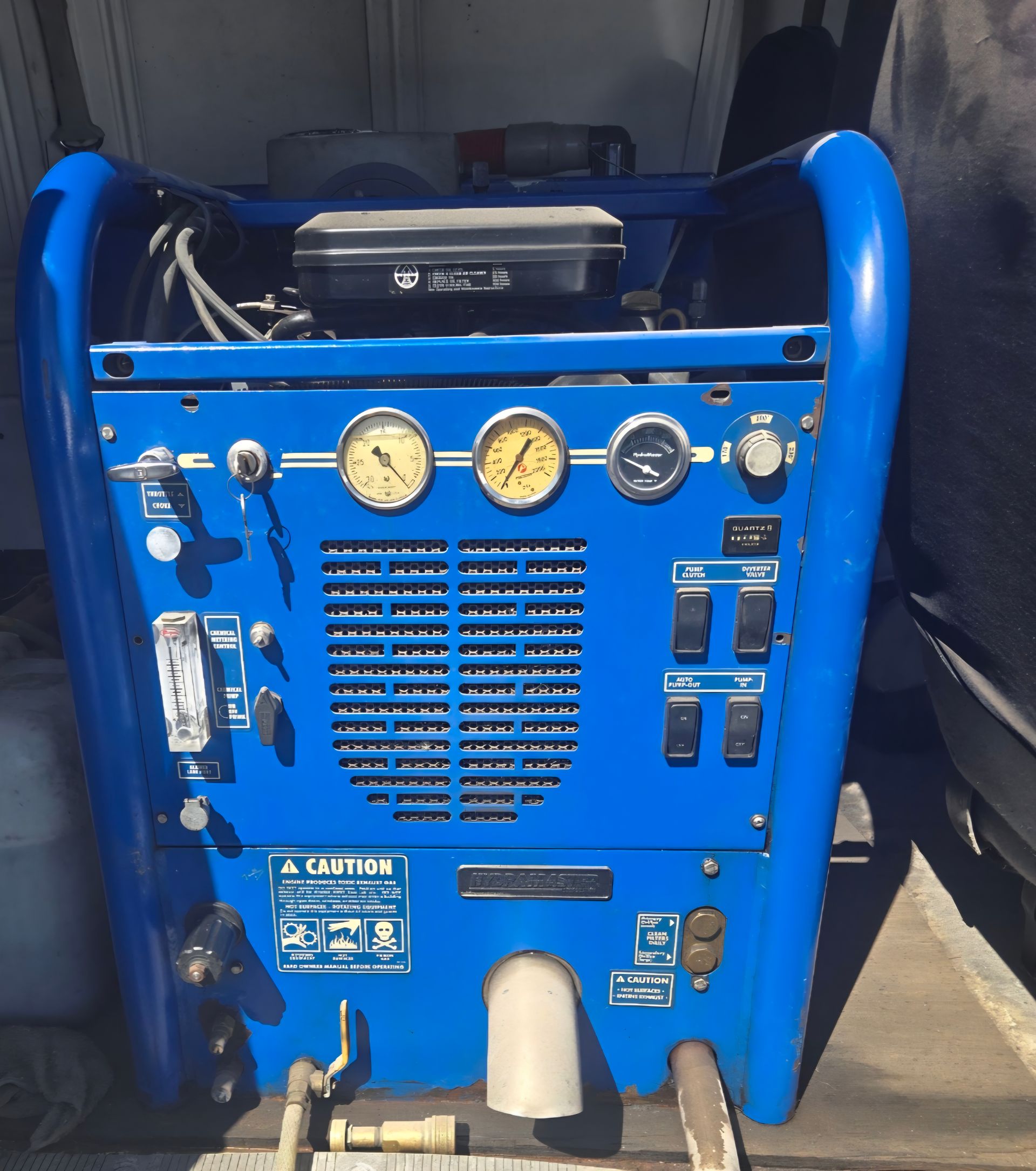 Blue carpet cleaning machine with gauges, switches, and a handle.