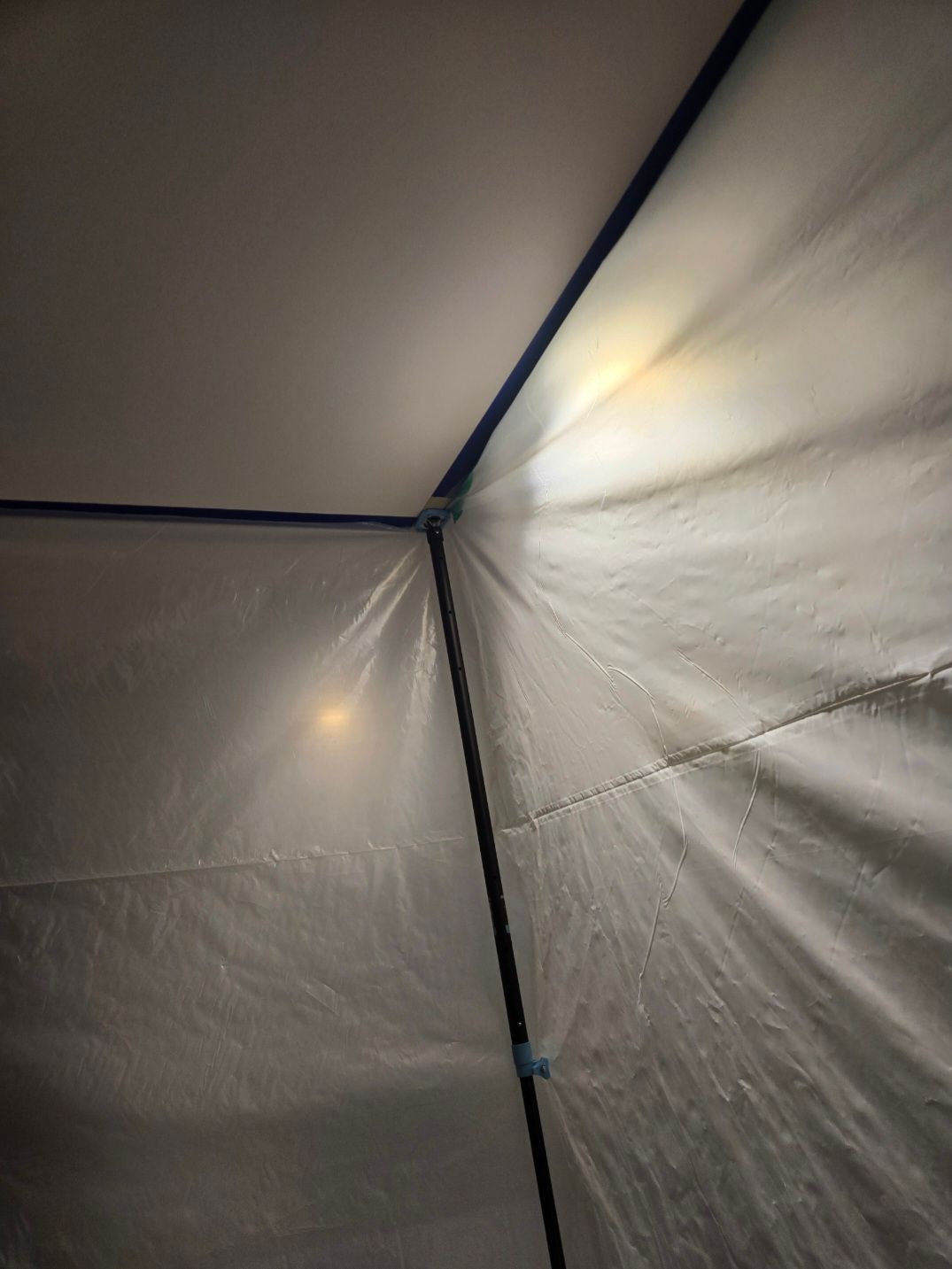 Inside a tent, two overhead lights illuminate the white fabric walls.