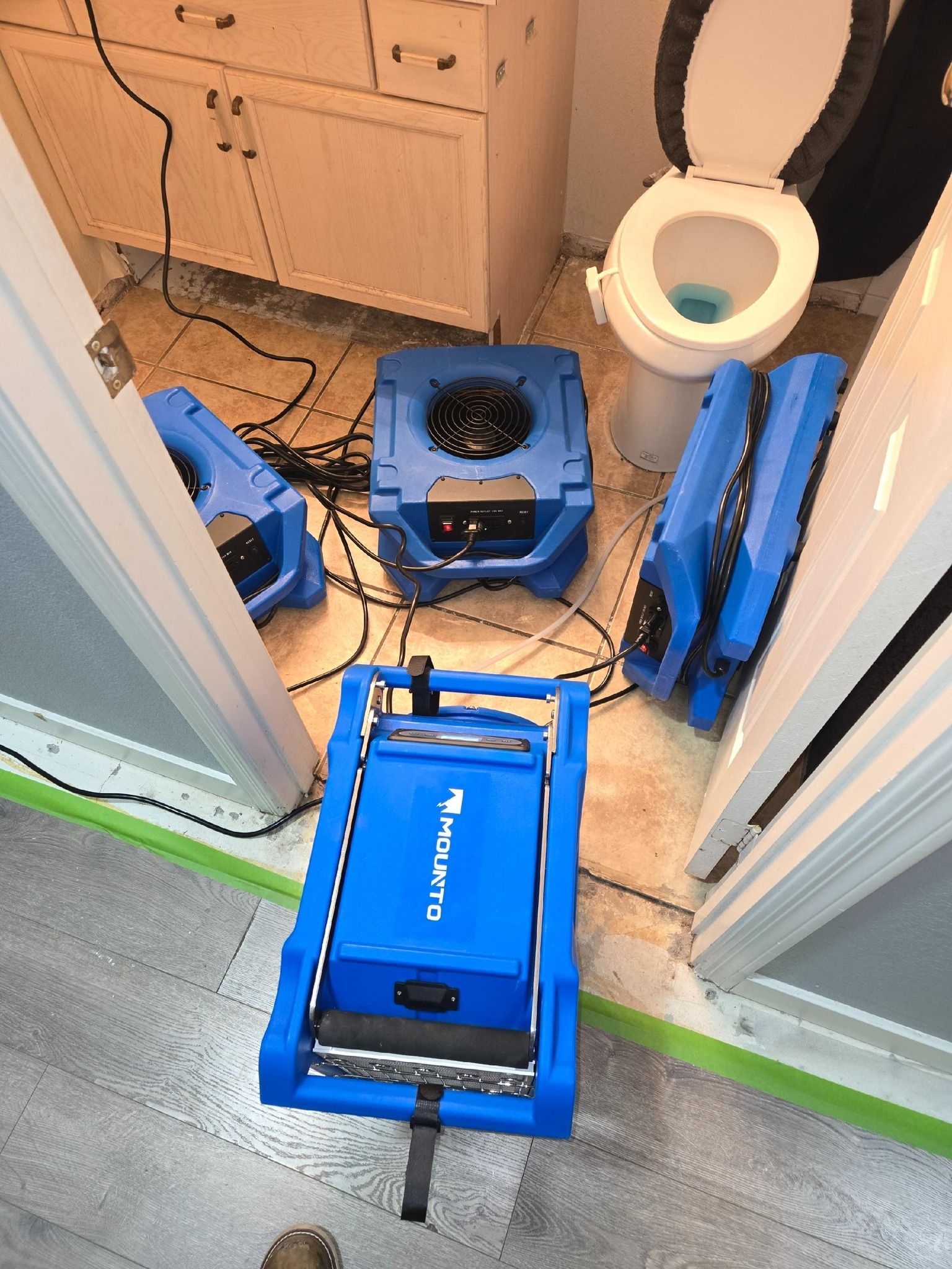 Blue water damage restoration equipment in a bathroom.