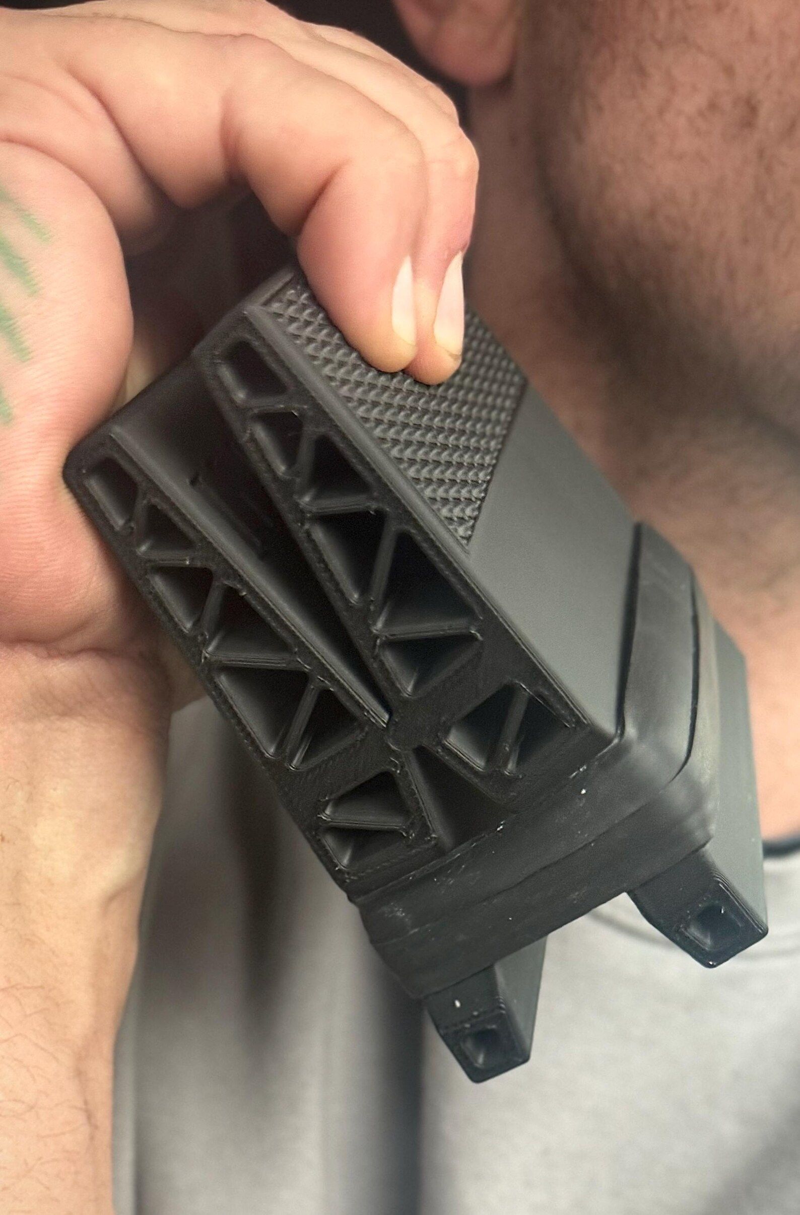 Hand holding black plastic grip tool with rubber band