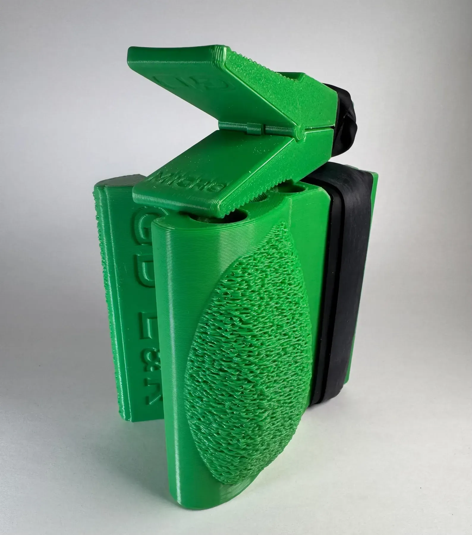A bright green, 3D-printed handle accessory for a handheld device, featuring a textured grip and a lever-style clamp.
