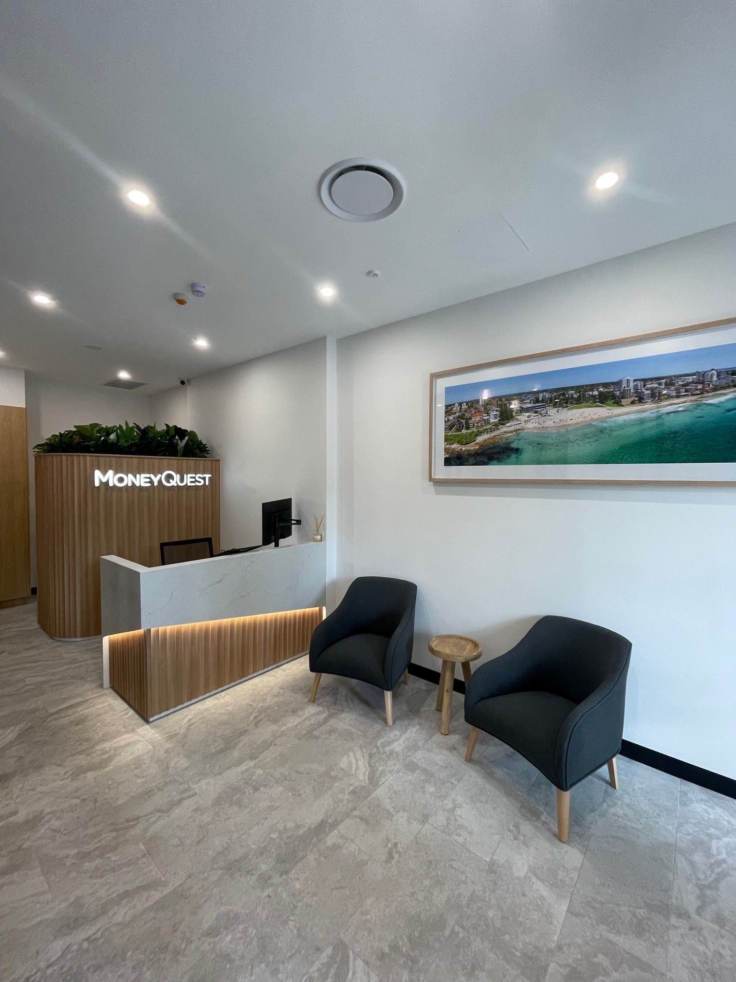 Modern office reception area with two armchairs, a small table, and a framed beach photo. The reception desk has a wooden front — ATH Projects in Kirrawee, NSW