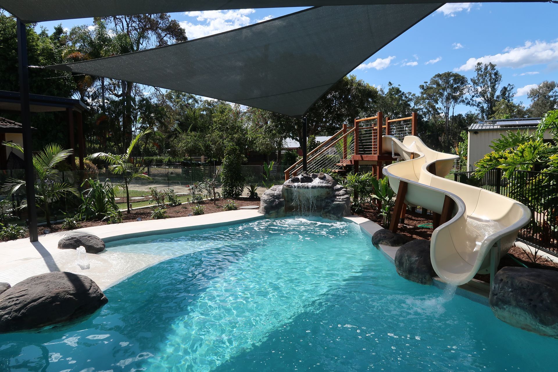 Swimming Pool With Water Slide, Waterfall, and Shade Sail — ATH Projects in Bellmere, QLD