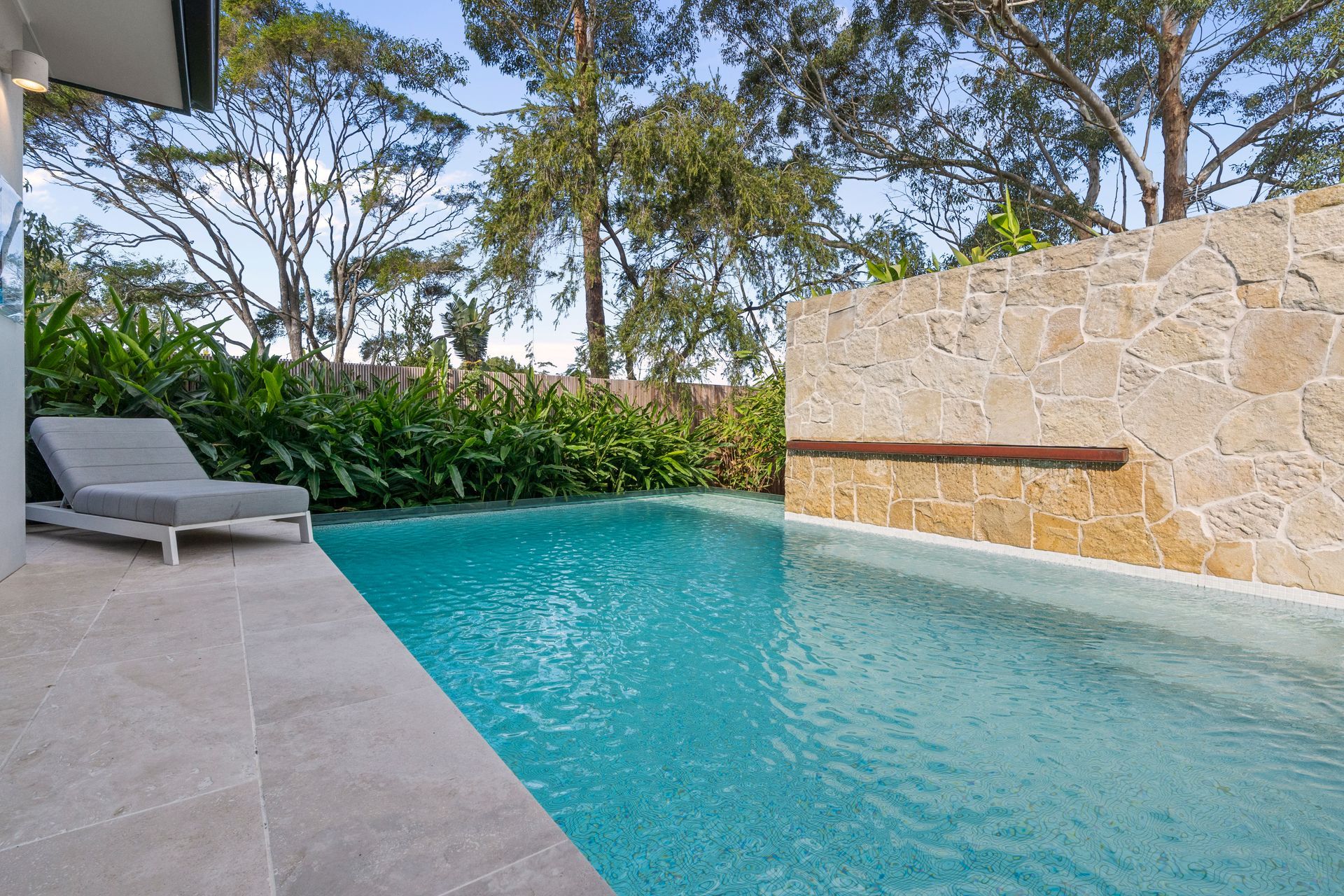 Pool With Turquoise Water Next to a Stone Wall and Chaise Lounge — ATH Projects in Yowie Bay, NSW