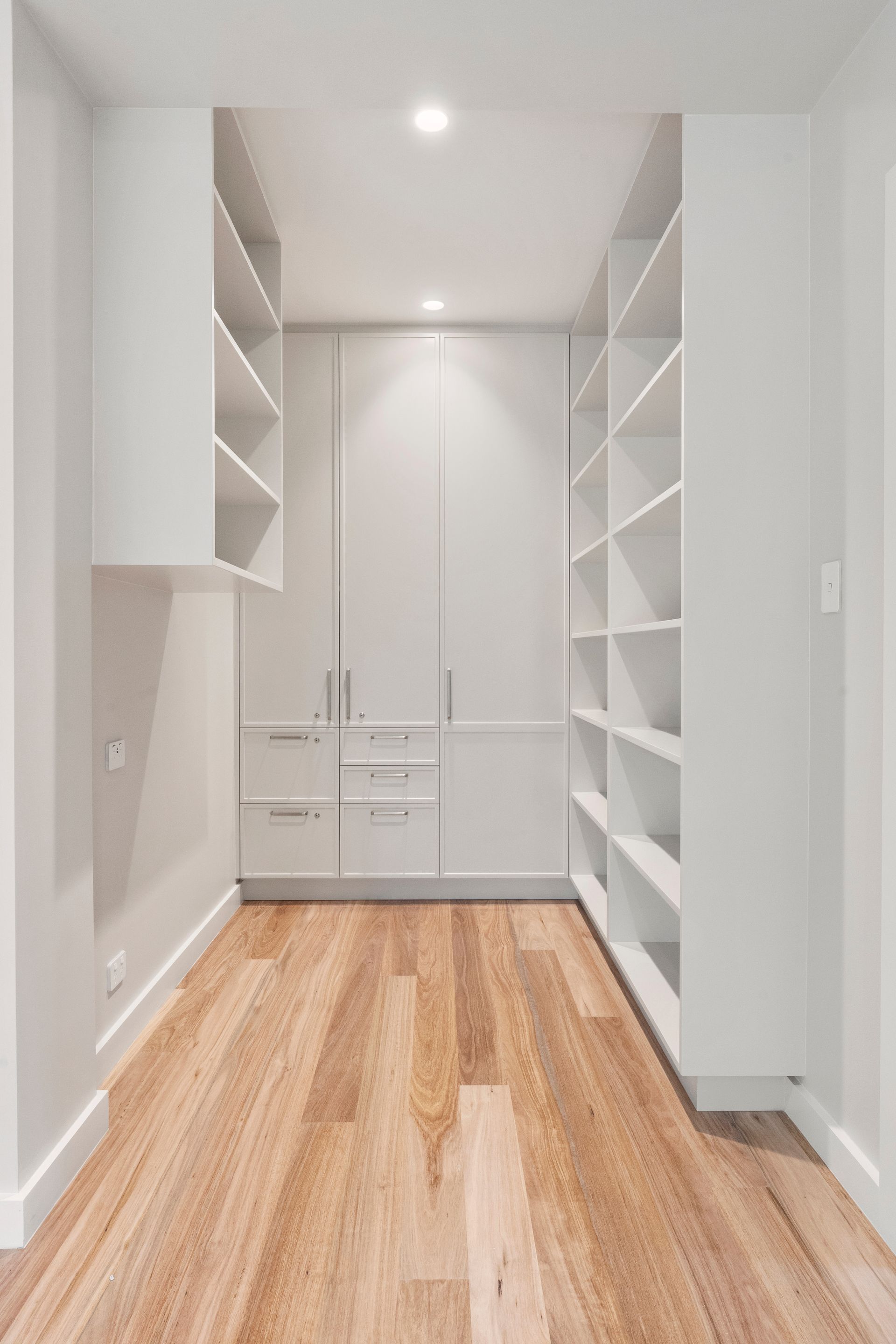 Walk-in Closet With Light Wood Floor, White Shelves and Cabinets — ATH Projects in Mosman, NSW