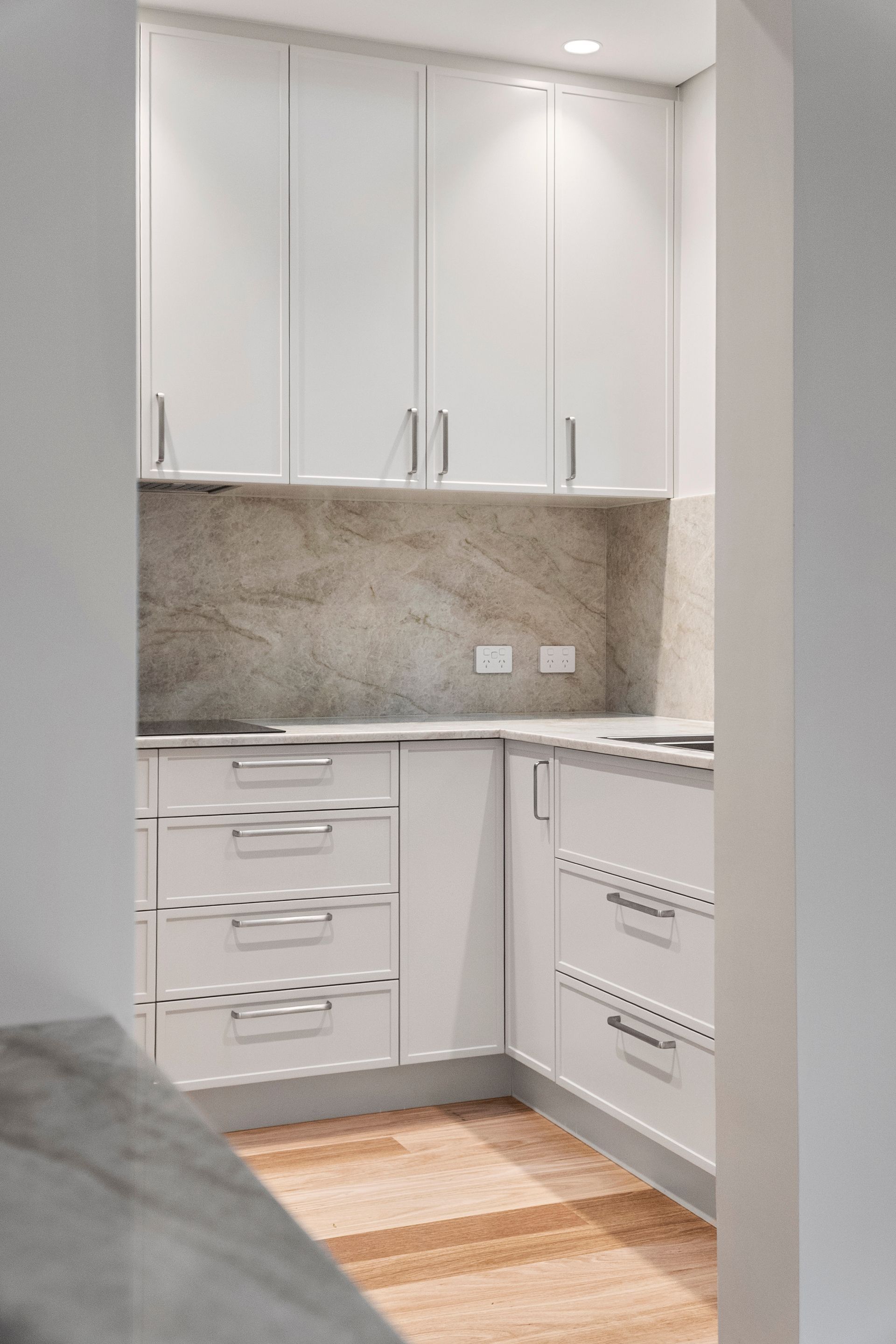 White Kitchen Cabinets With Silver Hardware, Beige Backsplash, and Wood Floor — ATH Projects in Mosman, NSW