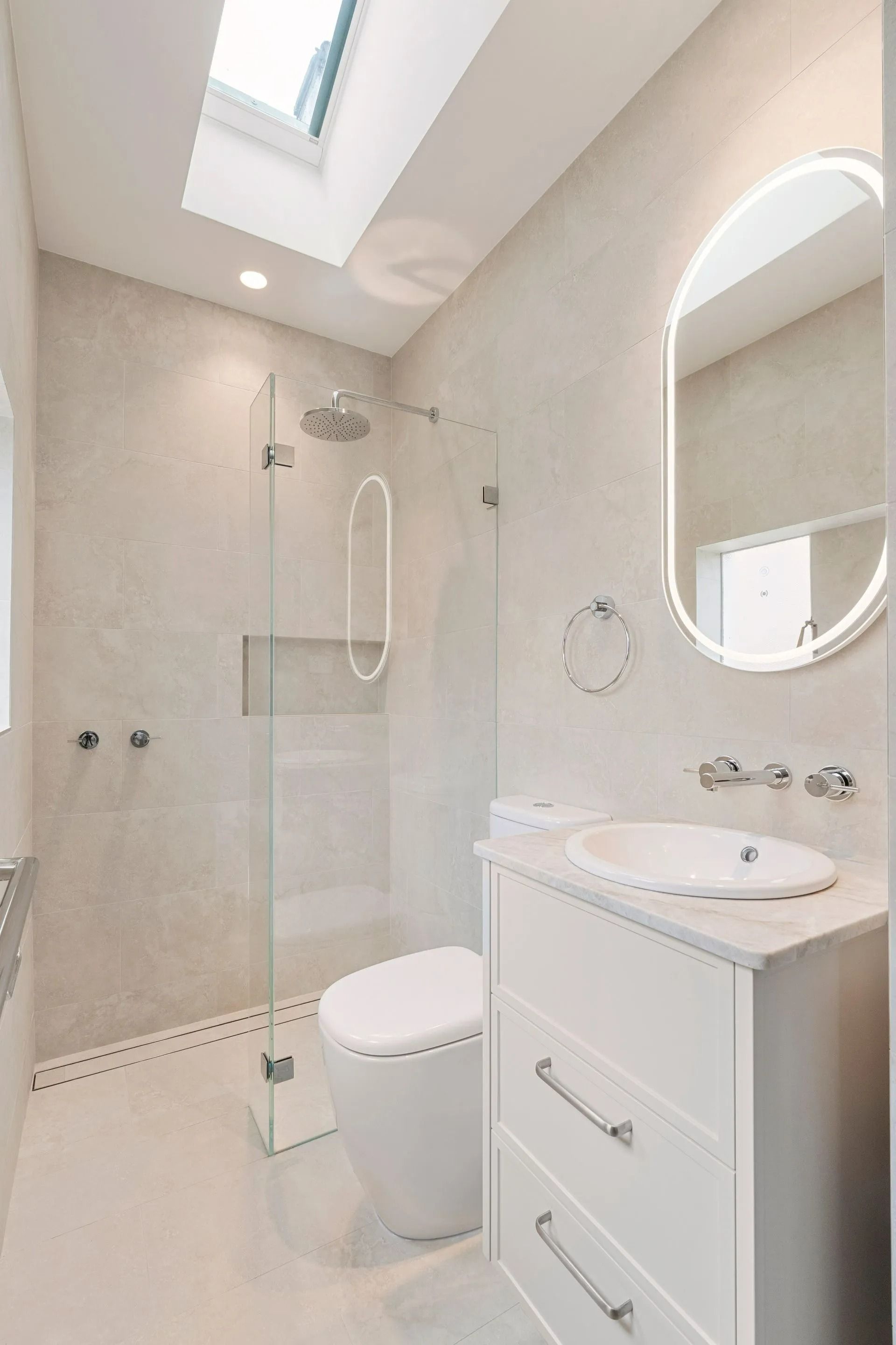 Modern White Bathroom With Shower, Toilet, Vanity, Oval Mirror, and Skylight — ATH Projects in Kirrawee, NSW