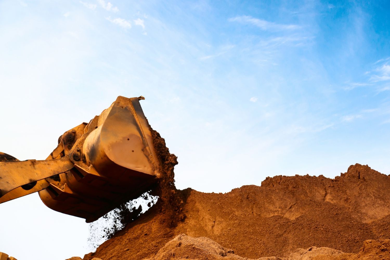 A bulldozer is scooping dirt from a pile of dirt.