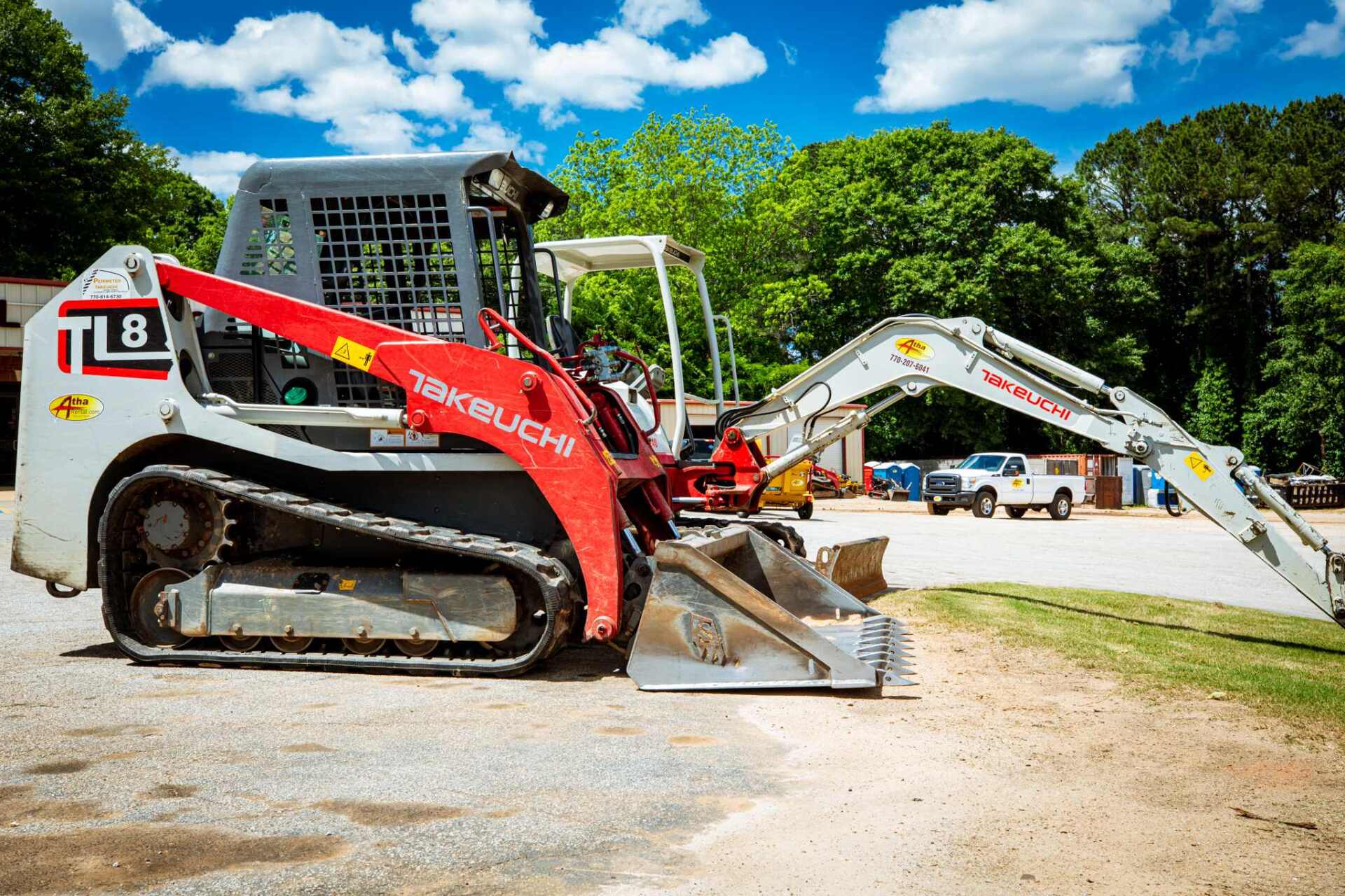 A bulldozer is parked next to an excavator in a parking lot.