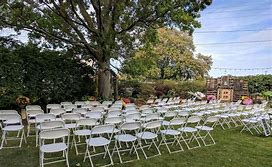 A row of white folding chairs sitting on top of a lush green field.