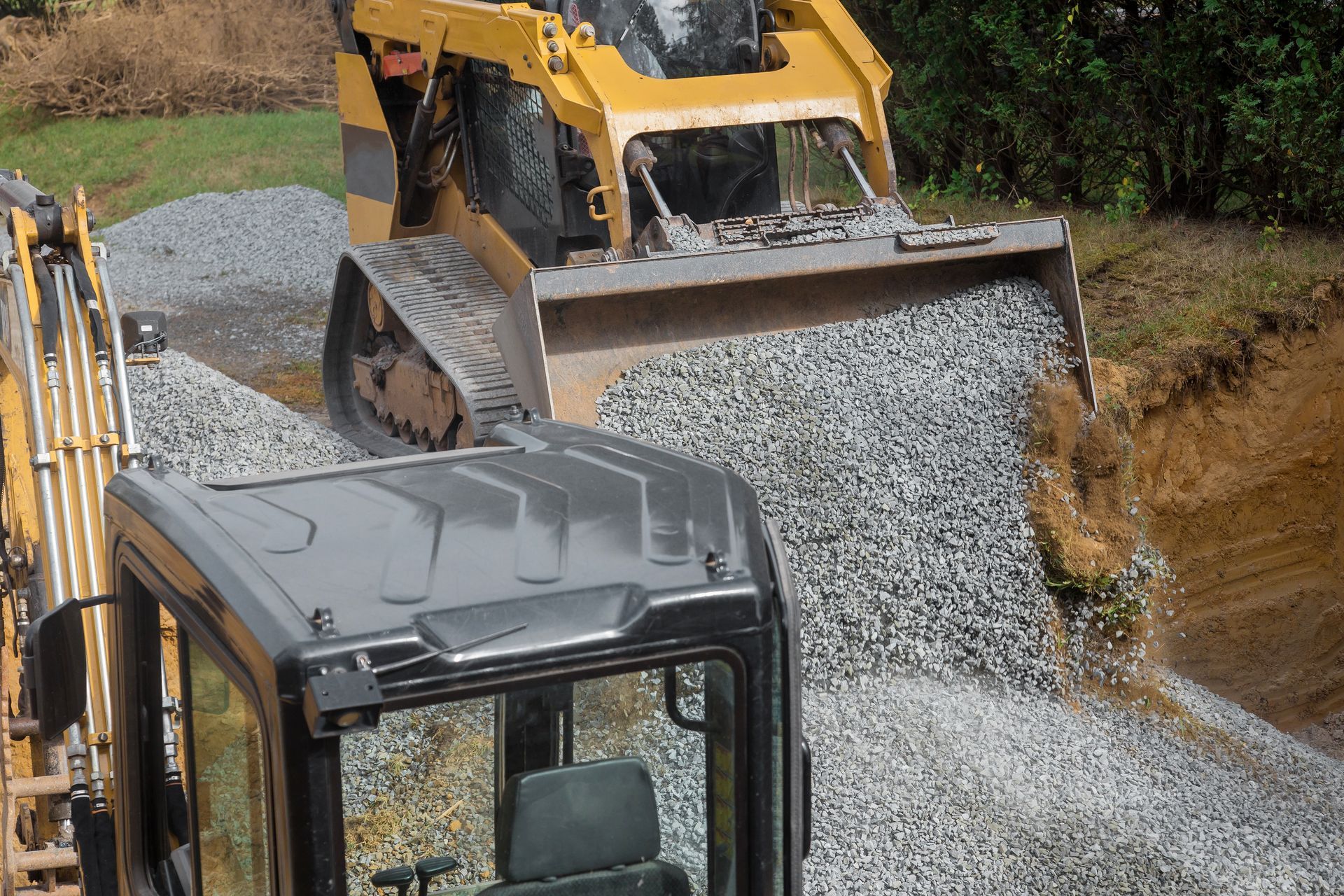 A bulldozer is loading gravel into a small excavator