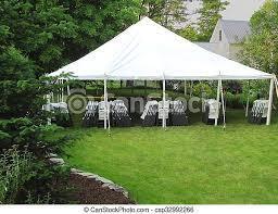 A large white tent with tables and chairs in a backyard.