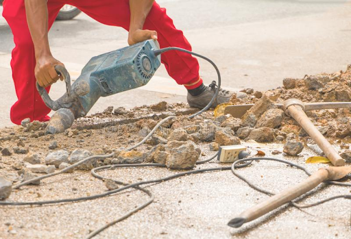 A man is using a hammer to break up concrete.