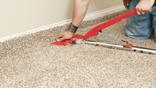 A person is cutting a piece of carpet with a tool.