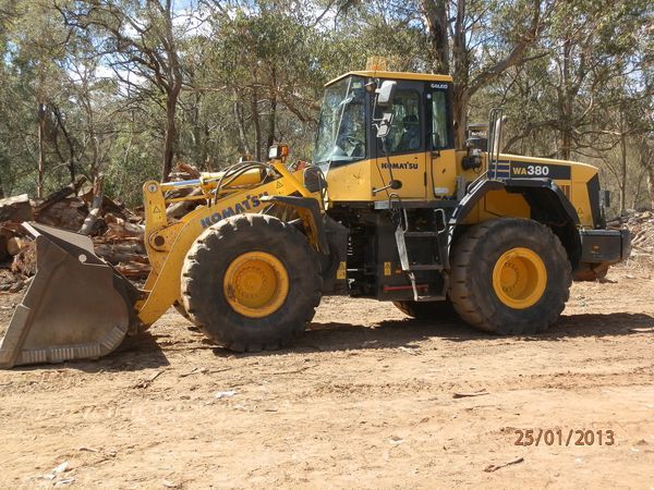 A yellow komatsu bulldozer is parked in the dirt