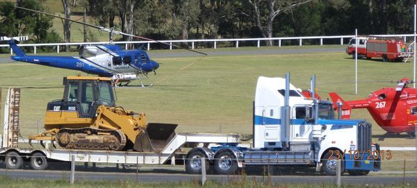 A truck is carrying a bulldozer and a helicopter.