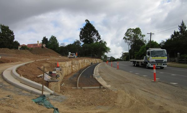 A truck with a flatbed is driving down a dirt road.