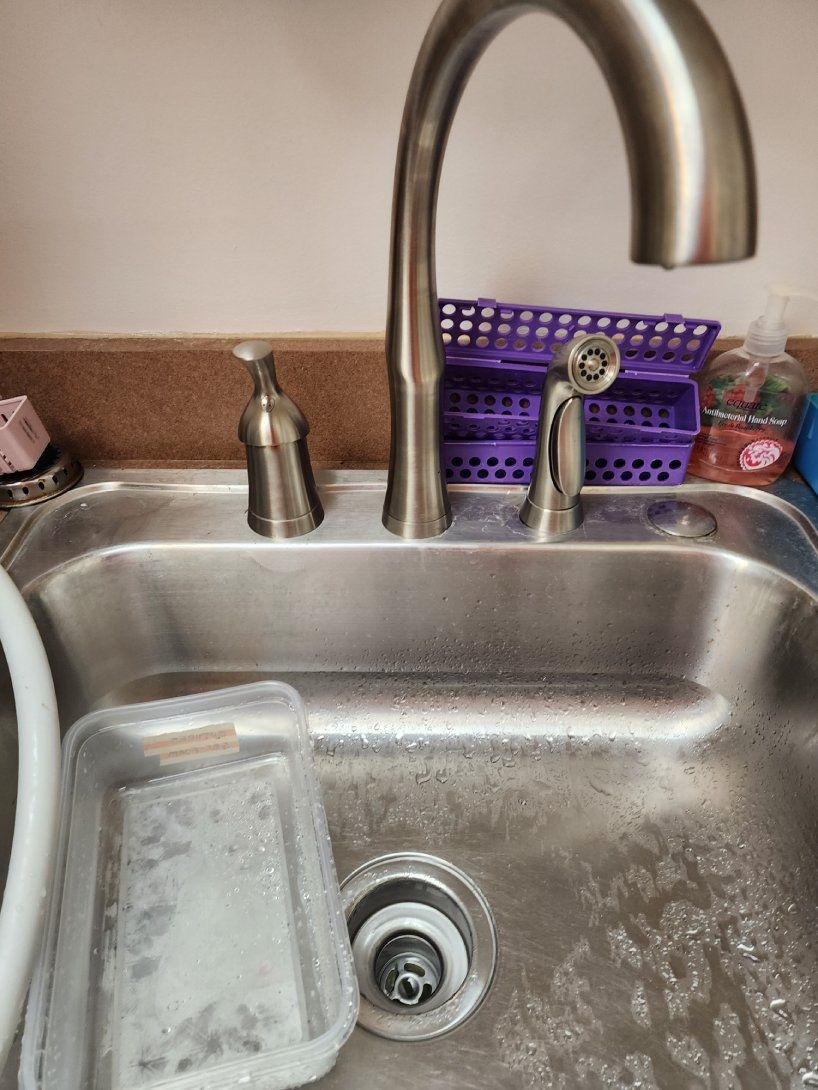 A faucet is covered in snow and ice and water is coming out of it.