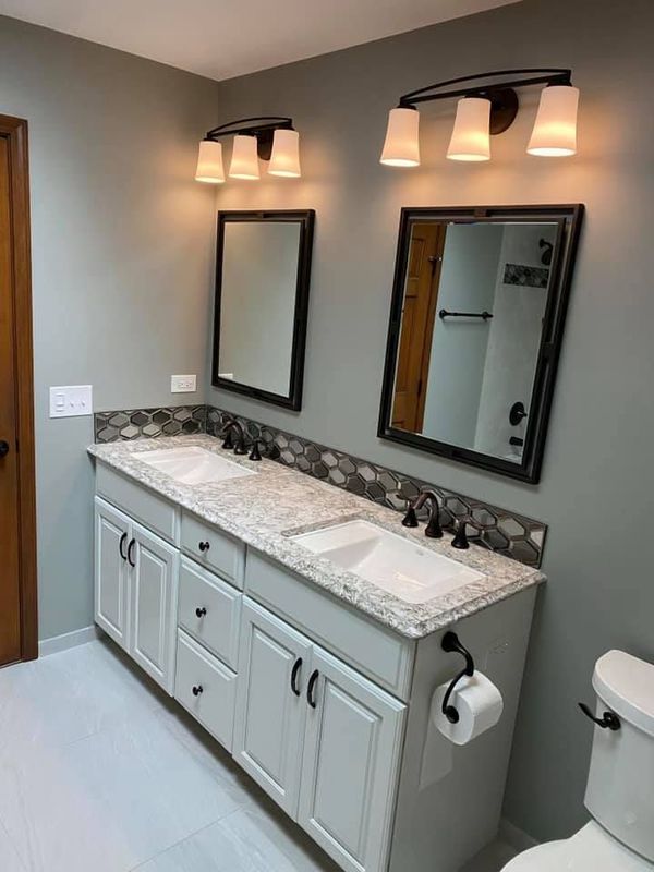 A & R Home Services remodel  bathroom with two sinks , two mirrors and a toilet.