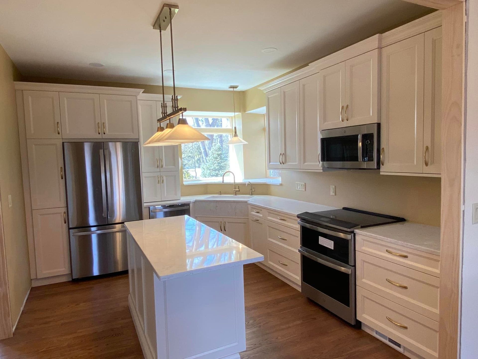 A & R Home Services remodel kitchen with white cabinets , stainless steel appliances and a large island.