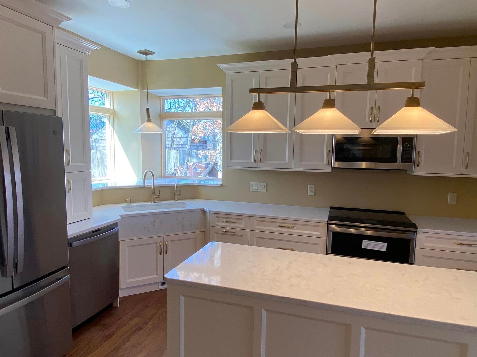 A & R Home Services remodel kitchen with white cabinets , stainless steel appliances and a large island.