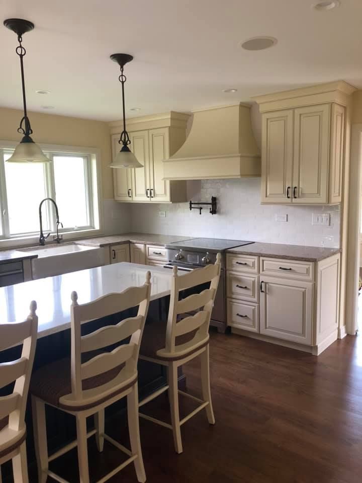 A & R Home Services  kitchen with white cabinets and stools and a large island