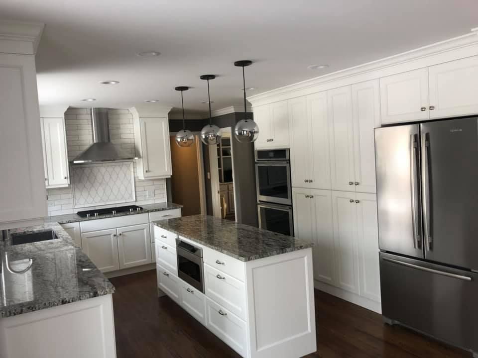 A & R Home Services  kitchen with white cabinets , granite counter tops , stainless steel appliances and a large island.