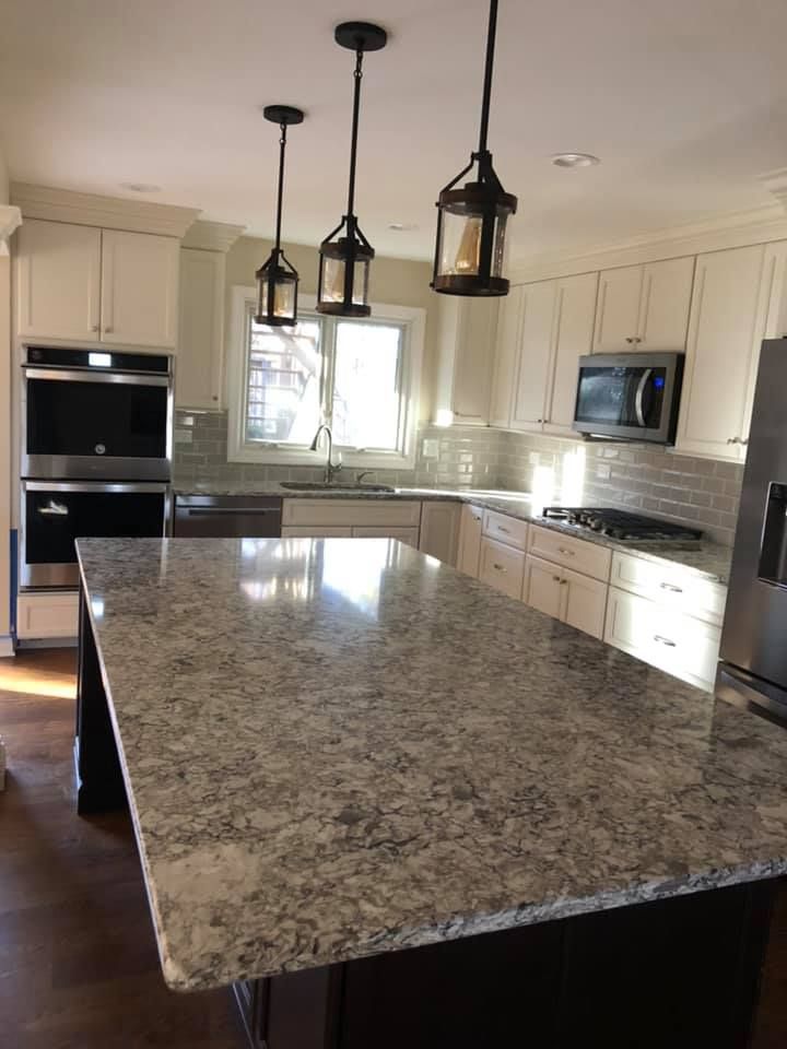 A & R Home Services  kitchen with white cabinets , granite counter tops , stainless steel appliances and a large island.