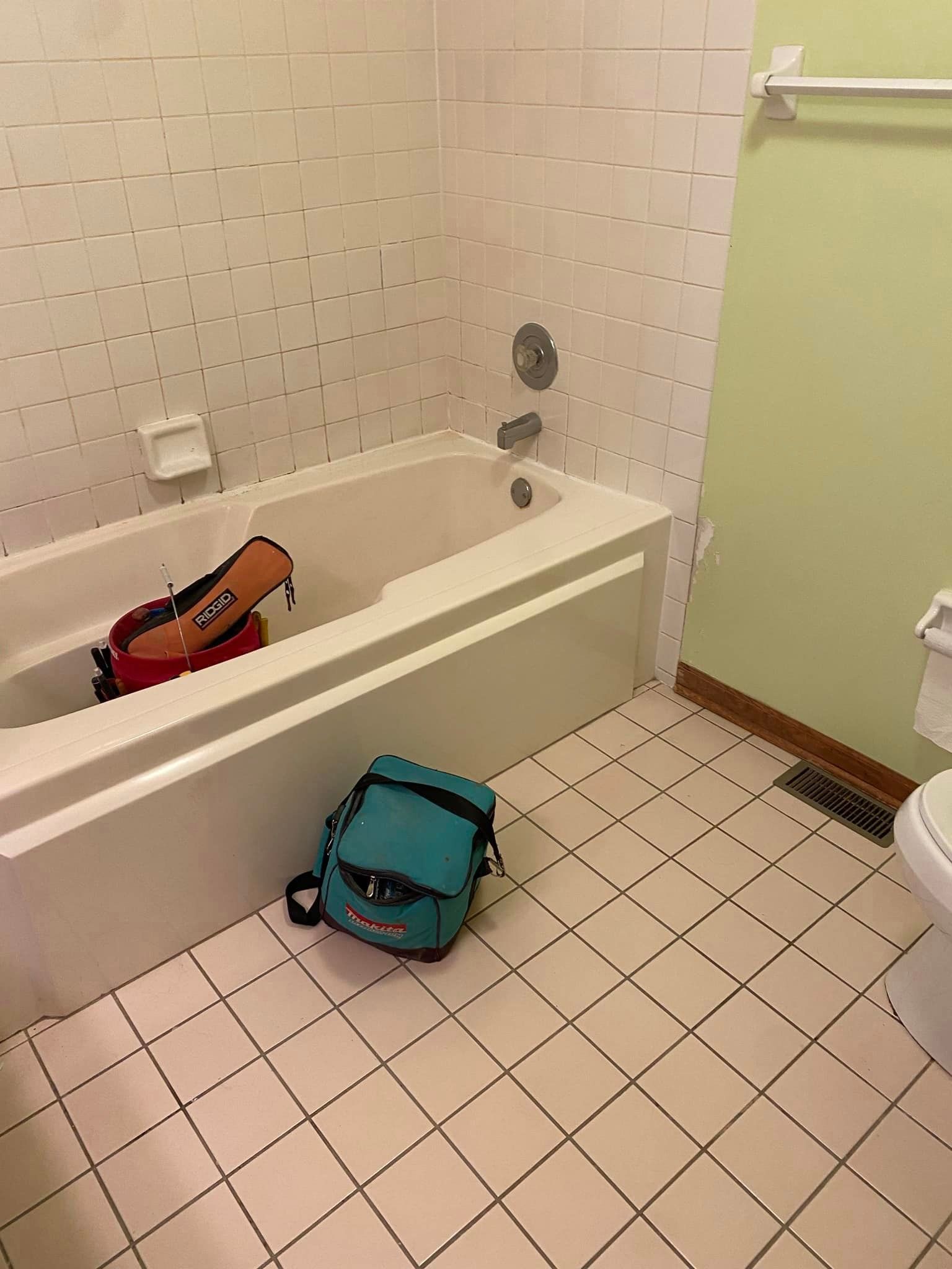 A & R Home Services remodel bathroom with a bathtub , toilet , and bag on the floor.