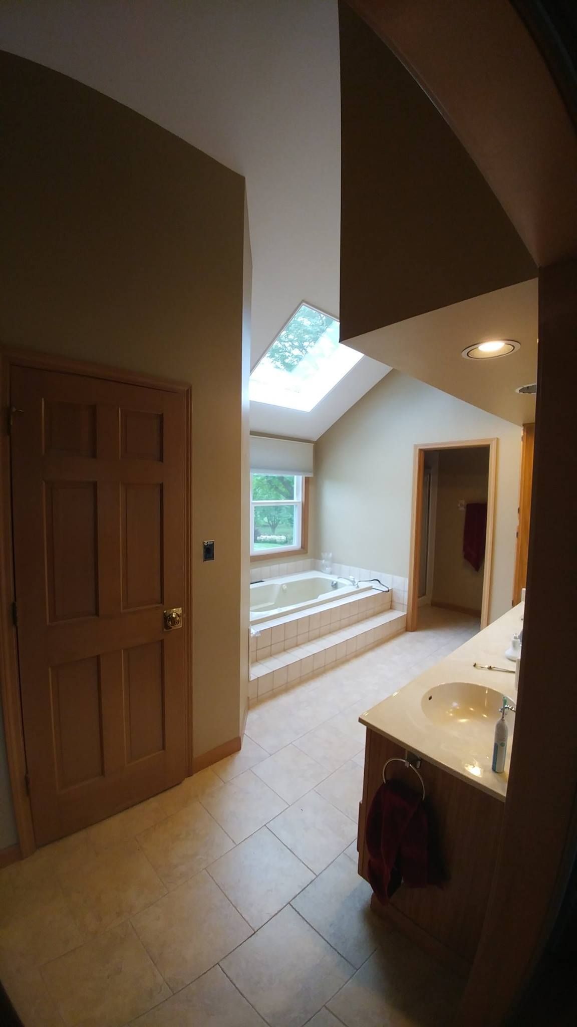 A bathroom with a skylight above the tub and a sink