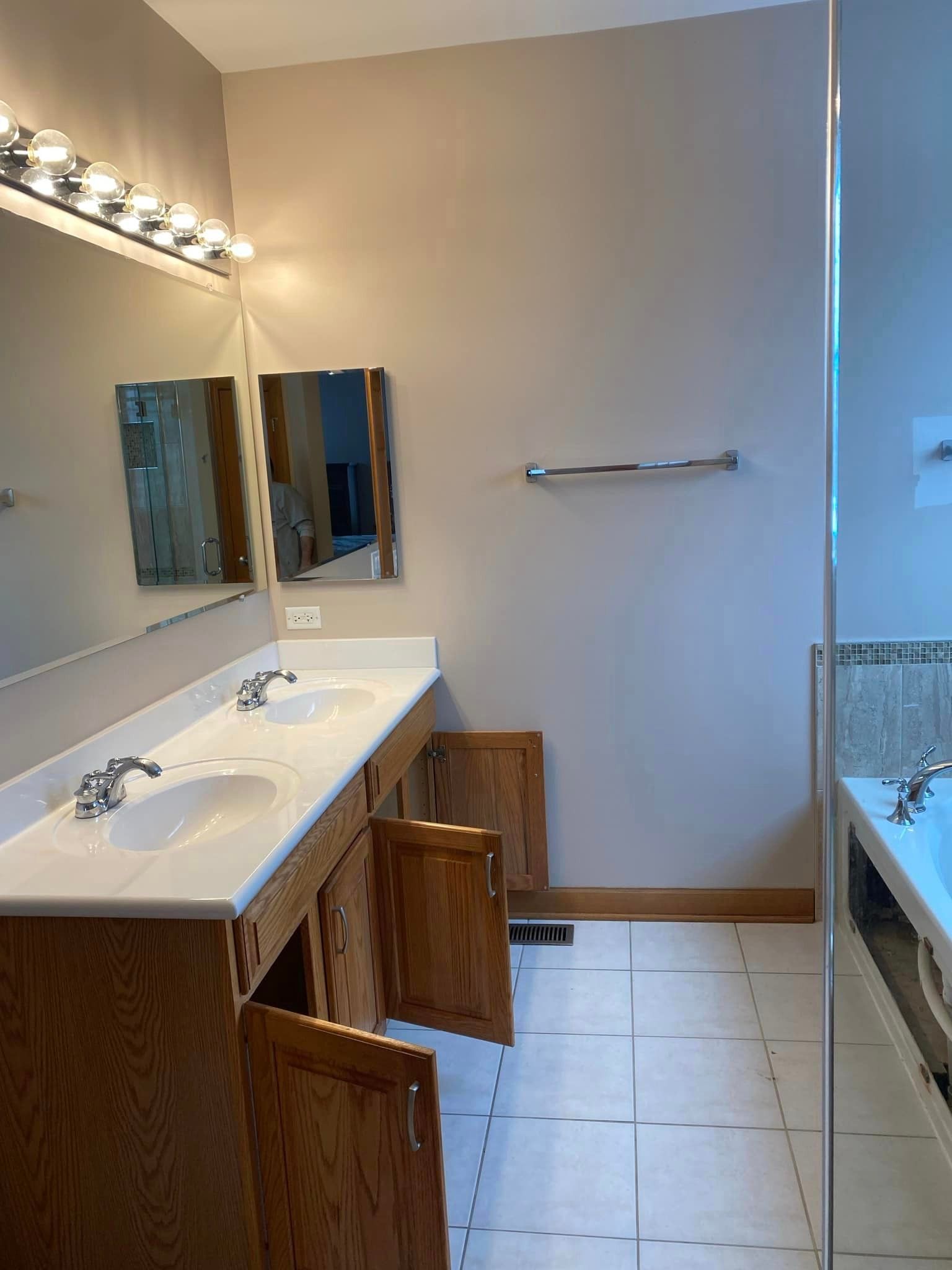 A & R Home Services remodel bathroom with two sinks , two mirrors and a bathtub.