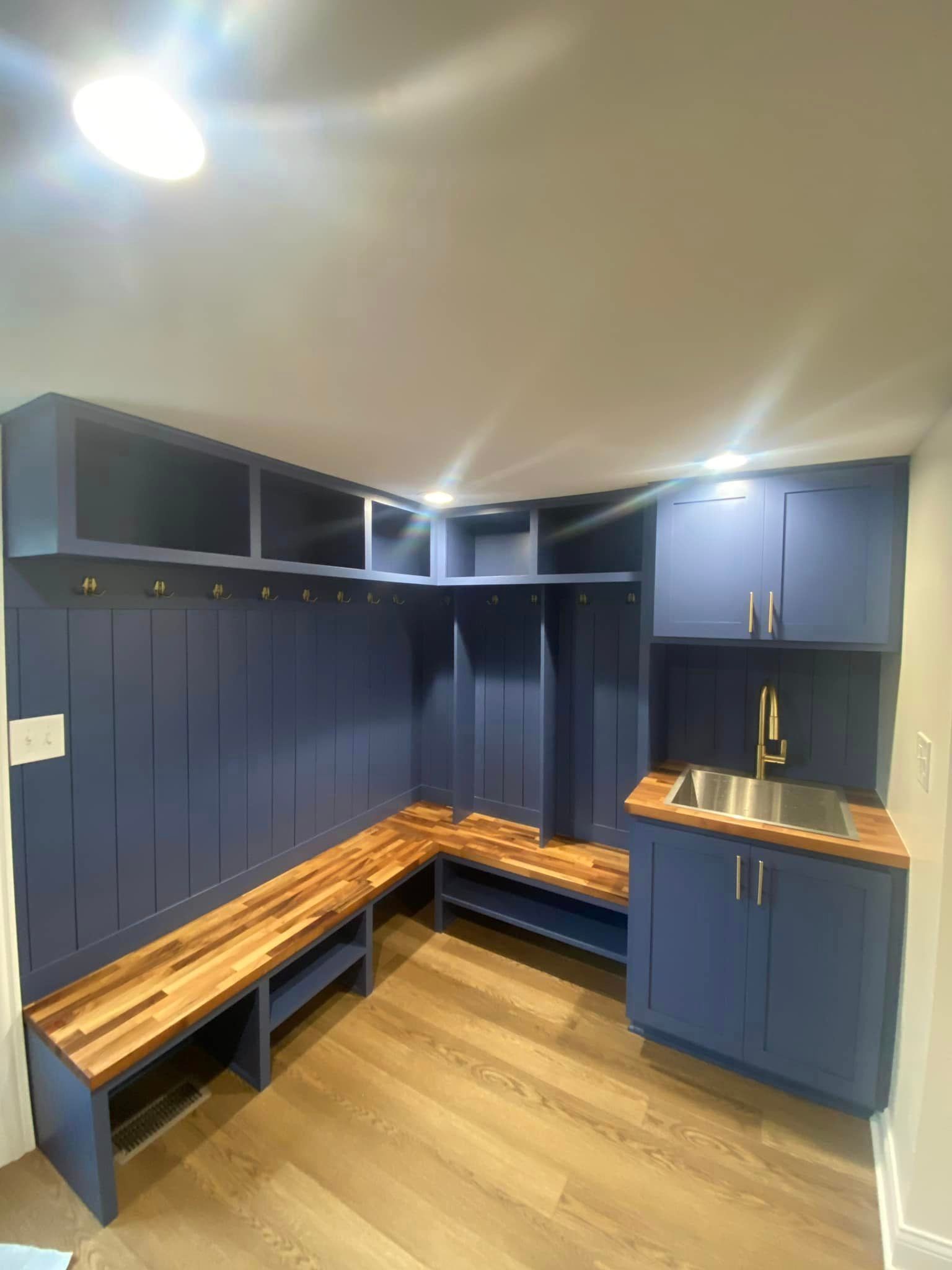 A & R Home Services remodel room with blue cabinets , a wooden bench , and a sink.