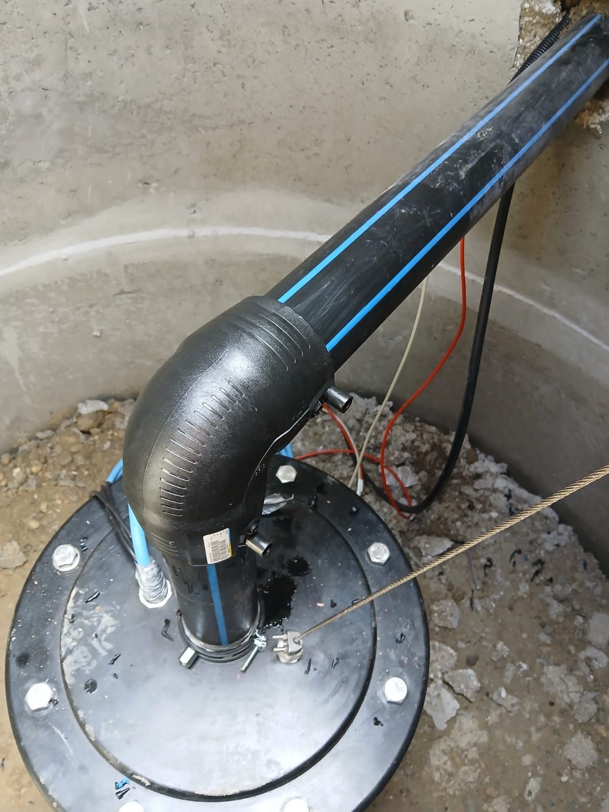 Ein schwarzes HDPE-Rohr mit einem 90-Grad-Winkelstück, das mit einer Brunnenkappenbaugruppe verbunden ist.