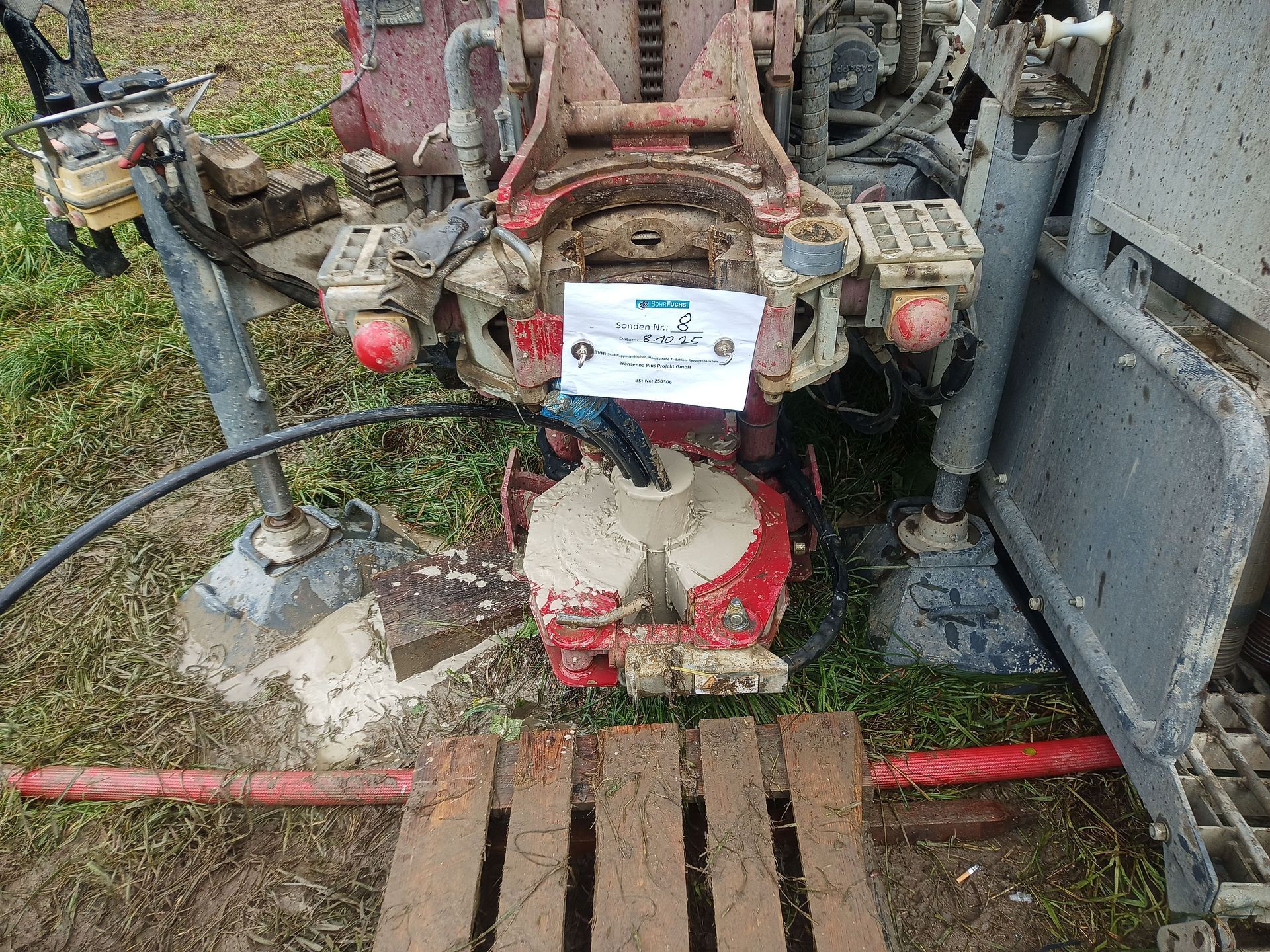 Nahaufnahme einer roten Industriebohranlage, die auf einem schlammigen Feld im Einsatz ist