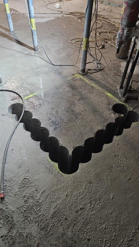 Eine Reihe sich überlappender kreisförmiger Löcher, die in einen Betonboden gebohrt wurden 