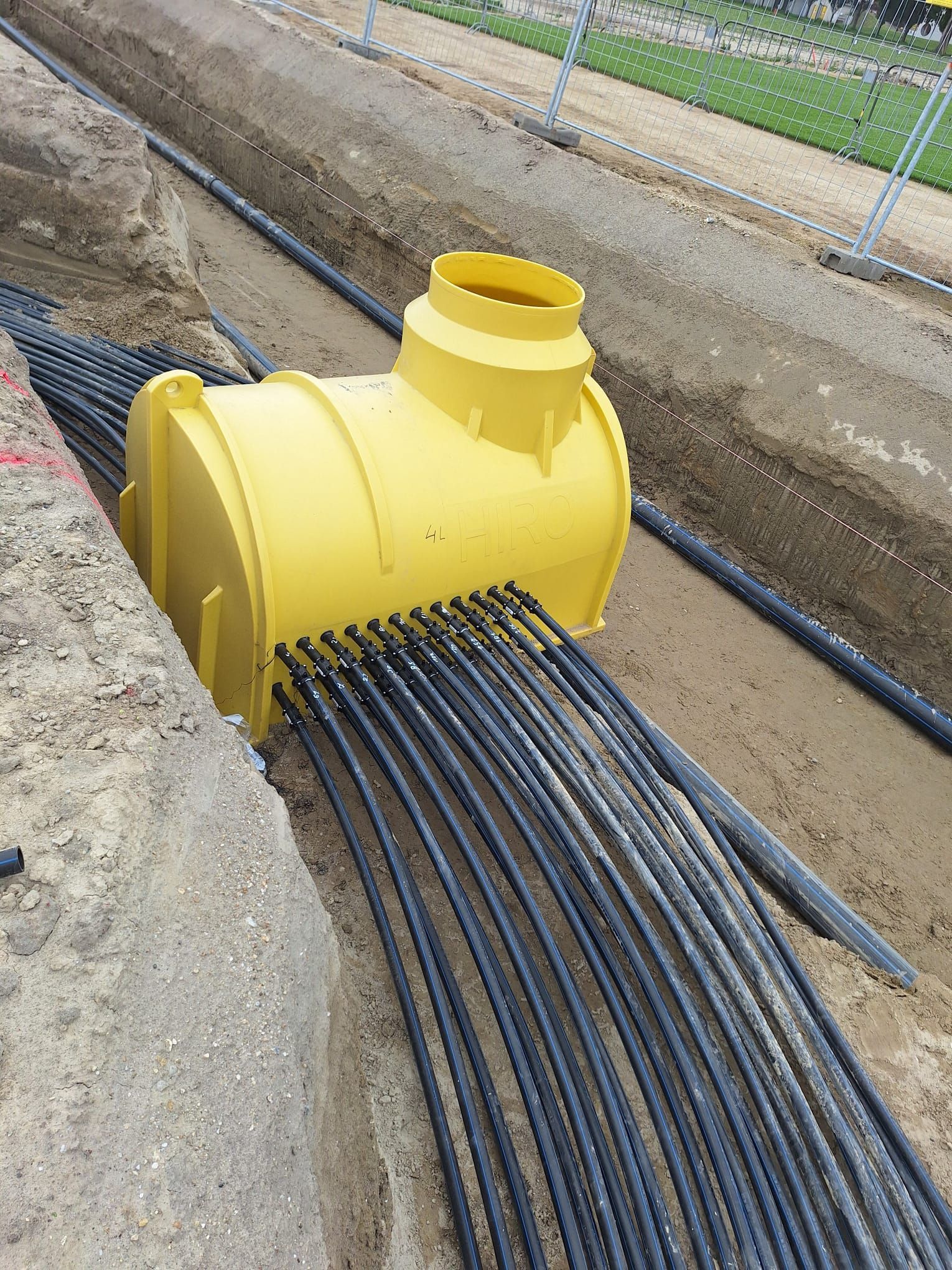 Ein gelber Kunststoff-Versorgungsschacht, der in einem Erdgraben installiert ist,