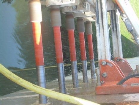 Eine auf einer Betonfläche montierte Baubohrmaschine verwendet mehrere rot-silberne Diamantbohrer