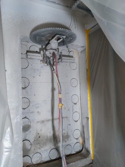 Eine an der Wand montierte Betonsäge mit einem großen kreisförmigen Diamantblatt, die über einem Wandabschnitt ist.