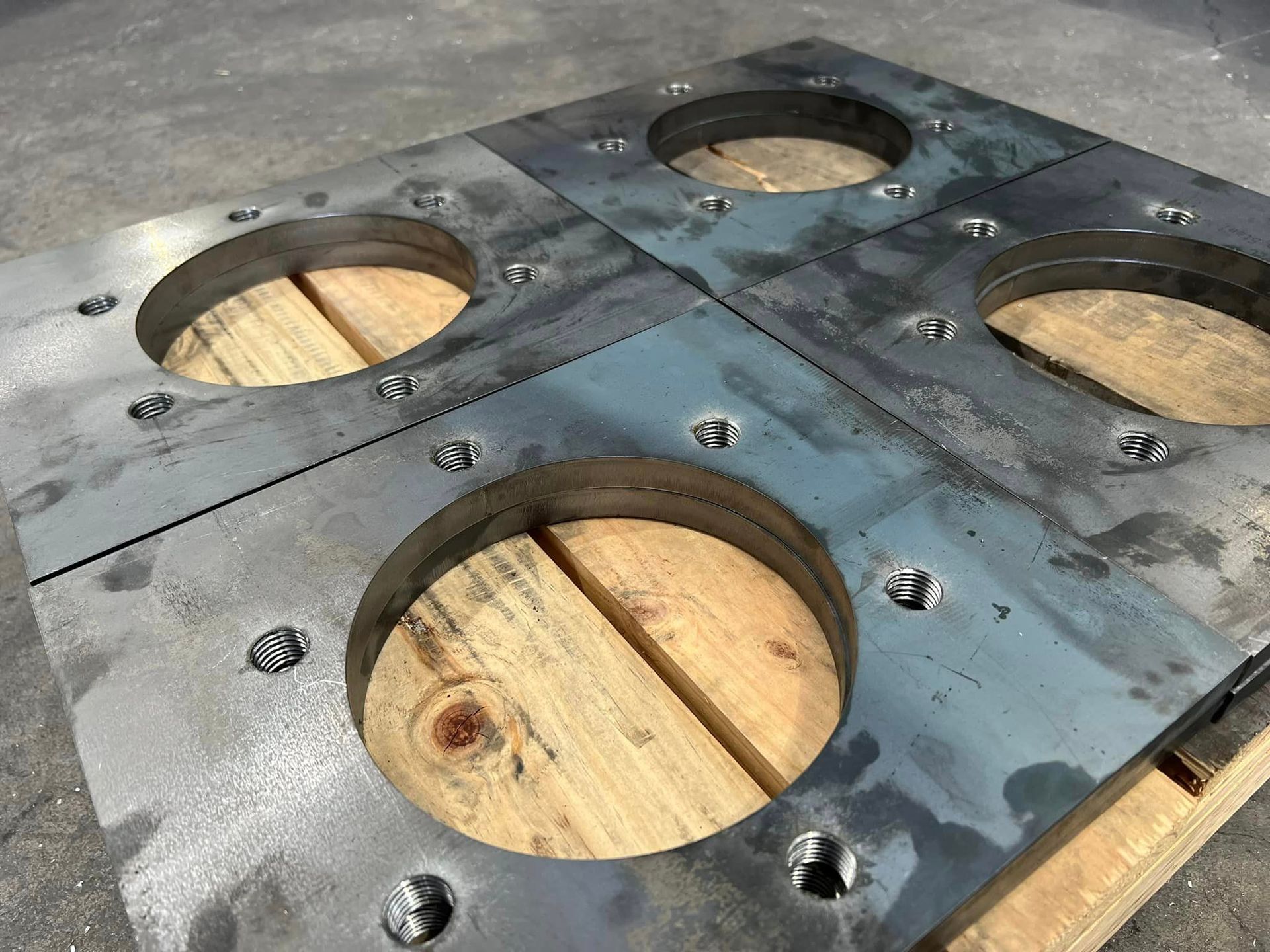 Four Metal Plates With Holes In Them Are Sitting On Top Of A Wooden Pallet – Wacol, QLD - Morgan Metal Corp