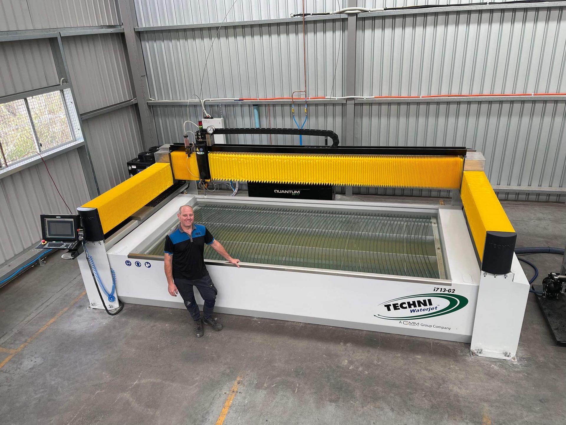 A man is standing next to a large machine in a warehouse.