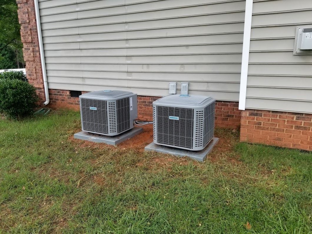 two air conditioners are sitting on the side of a house .