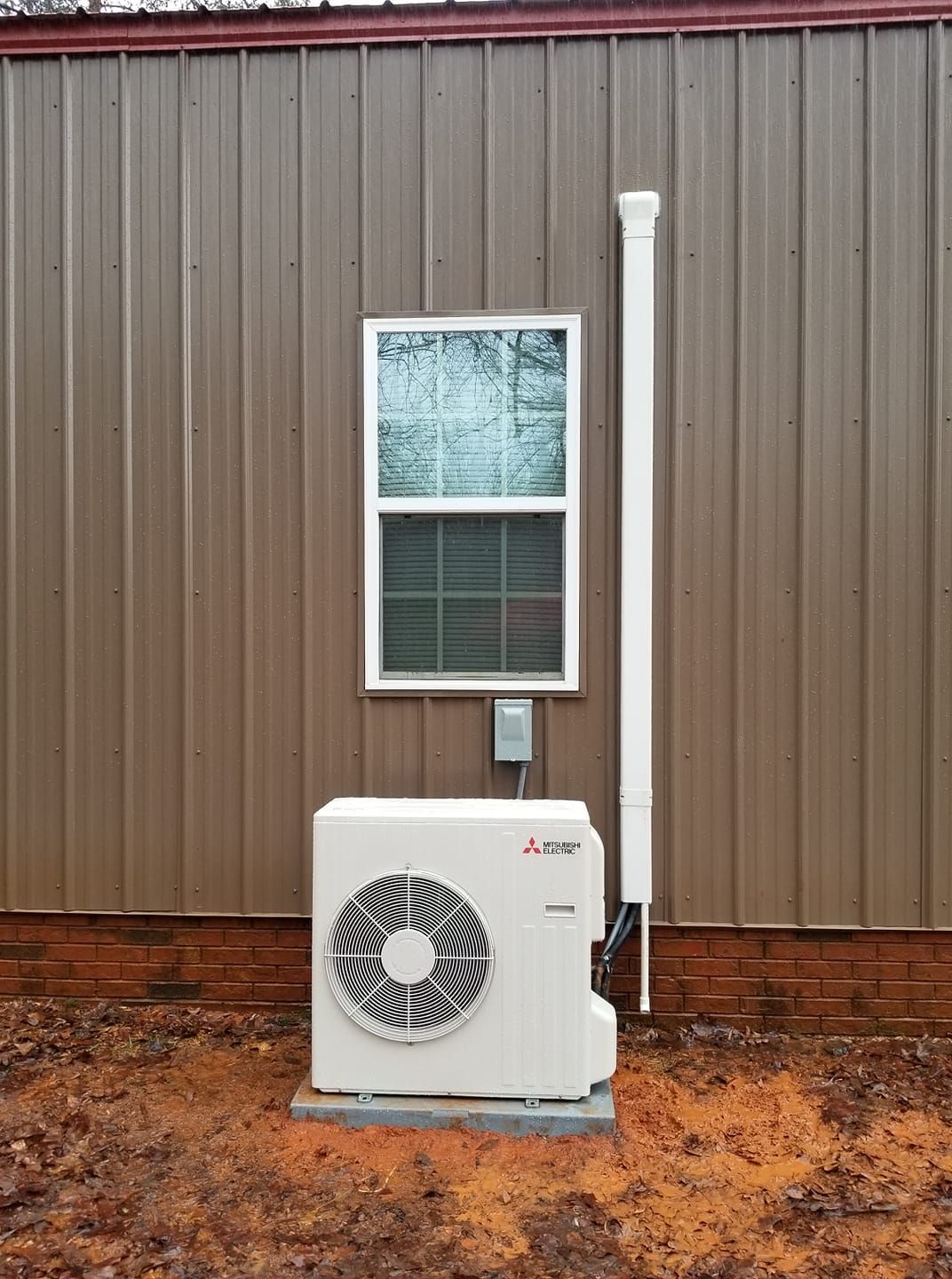 a white air conditioner is mounted on the side of a building next to a window .