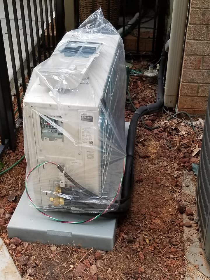 an air conditioner is wrapped in plastic and sitting on top of a concrete base .