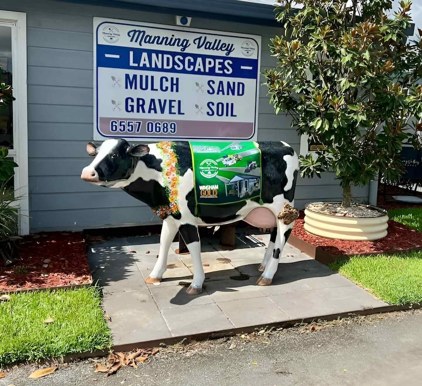 A Statue of a Cow in Front of a Sign for Manning Valley Landscapes — Manning Valley Landscapes in Wingham, NSW