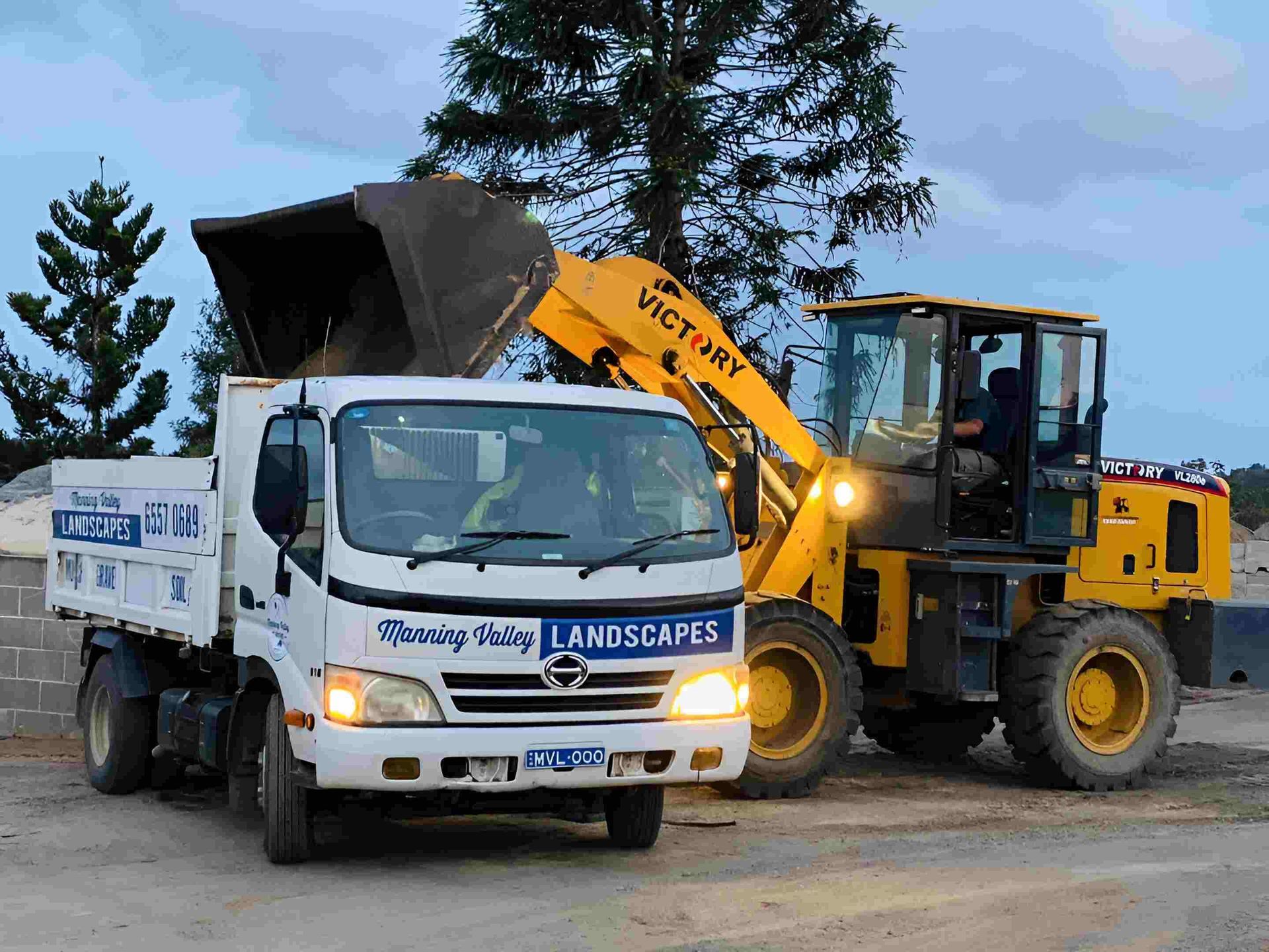 A Dump Truck and a Bulldozer Are Parked Next to Each Other — Manning Valley Landscapes in Wingham, NSW