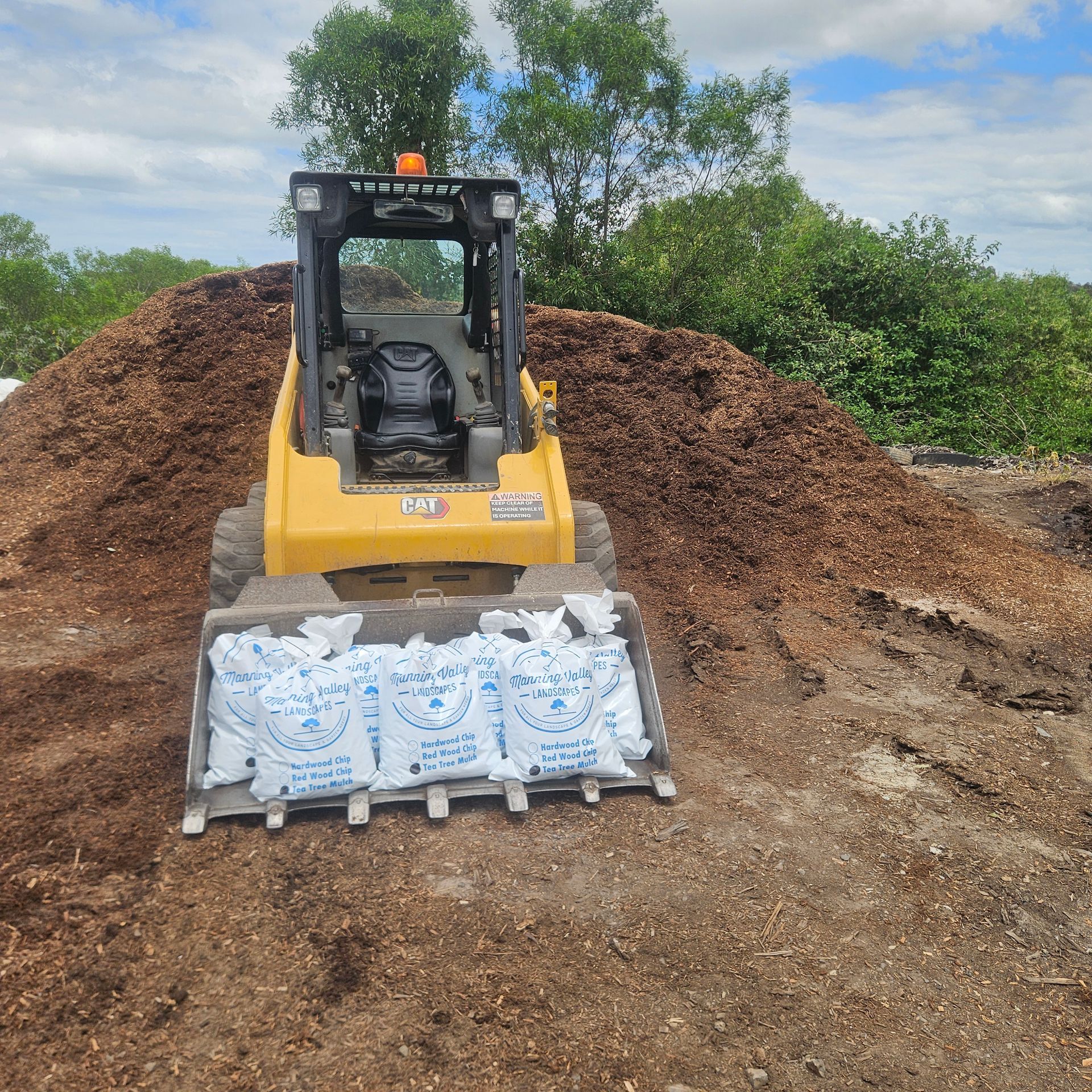 A Bunch of Bags of Mulch Are Sitting in Front of A Pile of Mulch — Manning Valley Landscapes in Wingham, NSW