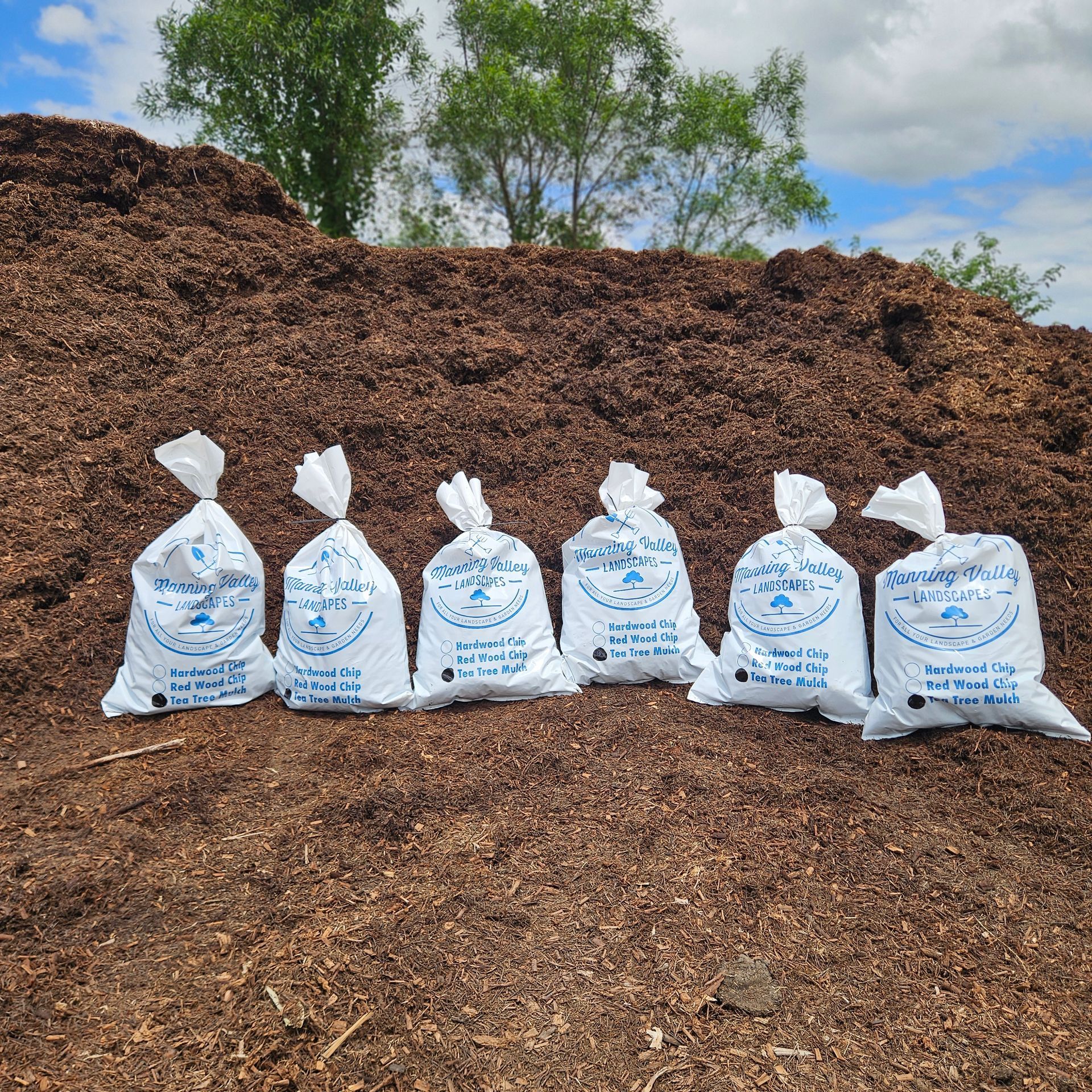 A Bunch of Bags of Mulch Are Sitting in Front of A Pile of Mulch — Manning Valley Landscapes in Wingham, NSW