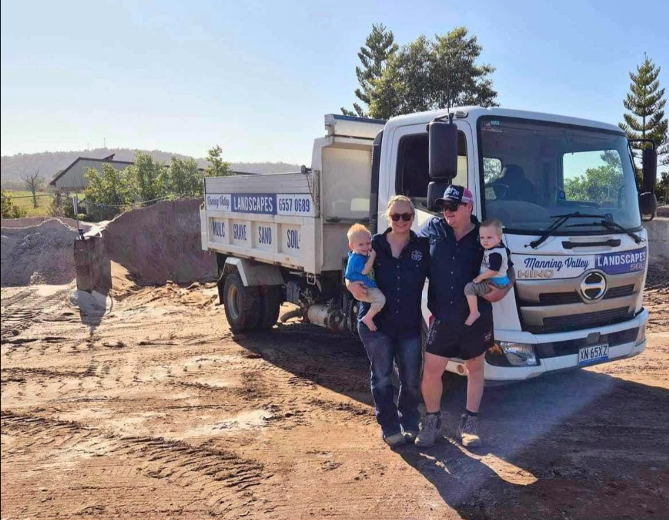 A family is standing in front of a dump truck. — Manning Valley Landscapes in Wingham, NSW