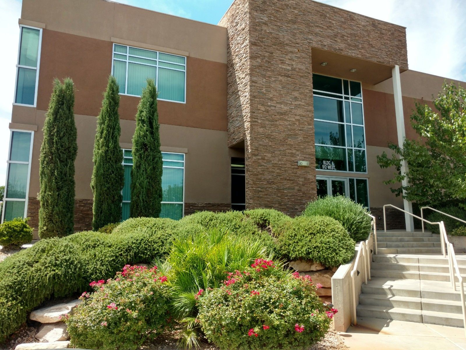 A large building with a lot of windows and bushes in front of it