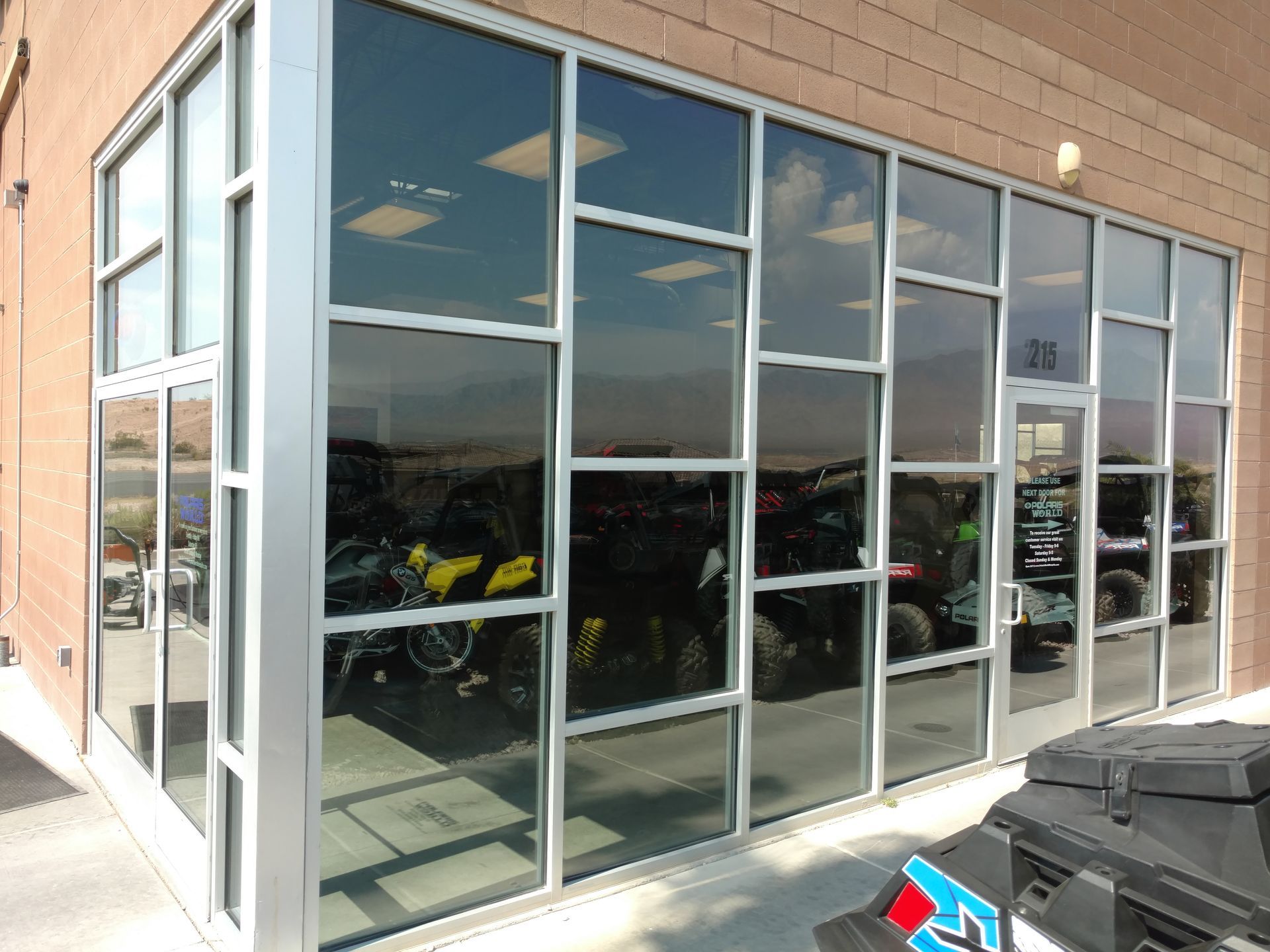 A motorcycle is parked in front of a building with a lot of windows.